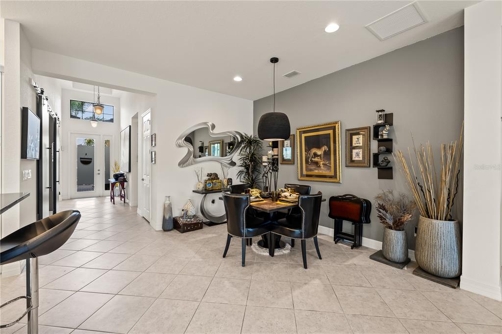 A dining area features a square table, black chairs, and a gray accent wall — 10035 CHESAPEAKE BAY DRIVE, FORT MYERS, FL