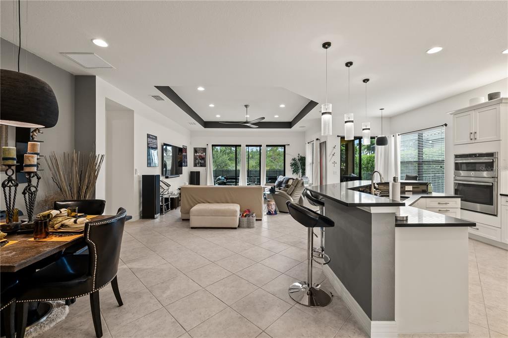 An open-concept kitchen and living area features tile floors, a tray ceiling, and a breakfast bar — 10035 CHESAPEAKE BAY DRIVE, FORT MYERS, FL