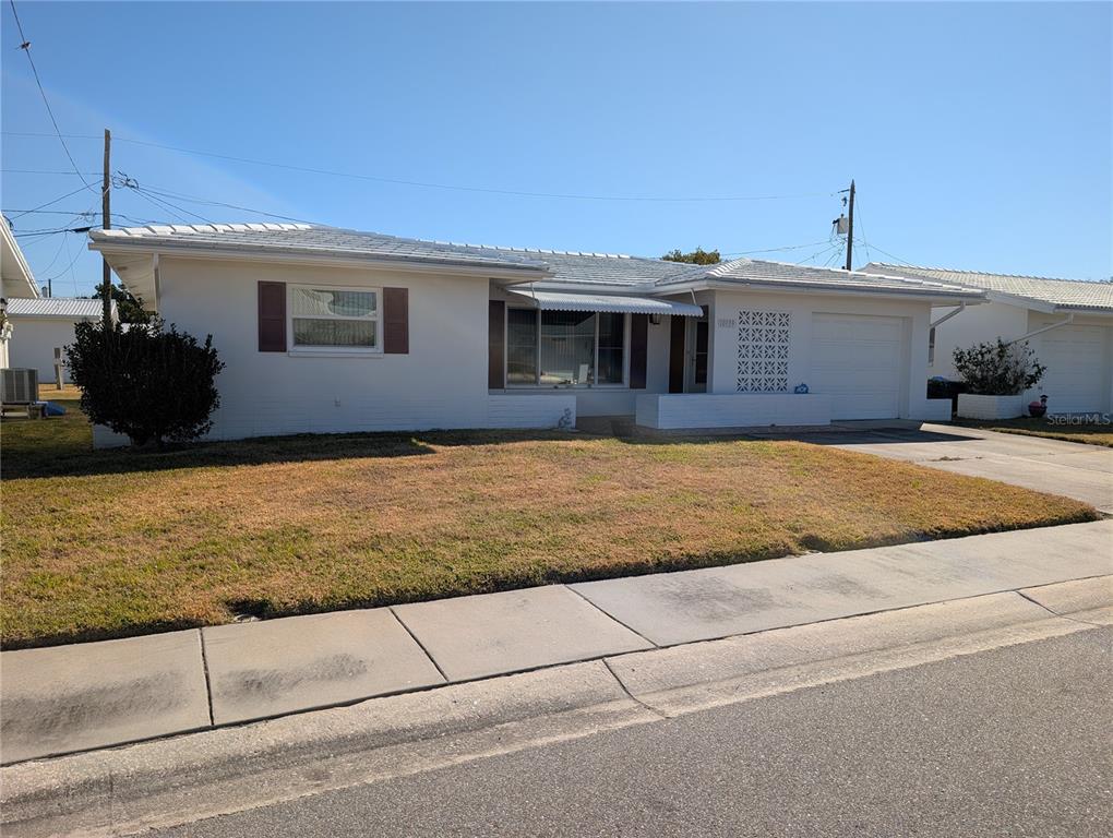 A single-story white house with a garage, a decorative screen wall, and a front lawn — 10139 44TH WAY N, PINELLAS PARK, FL