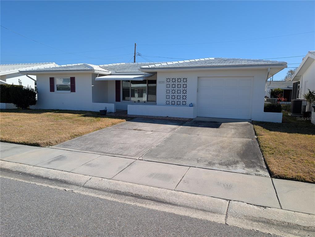 A single-story white house with a concrete driveway, a garage, and decorative breeze block accents — 10139 44TH WAY N, PINELLAS PARK, FL