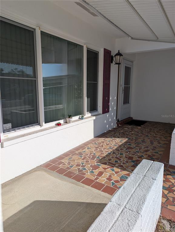 A covered porch features a mosaic-tiled floor, a large window, and a white front door — 10139 44TH WAY N, PINELLAS PARK, FL