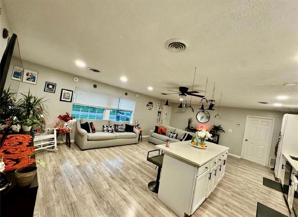 An open-concept living room and kitchen featuring light wood flooring and a central island — 5832 HOLMES DRIVE, ORLANDO, FL