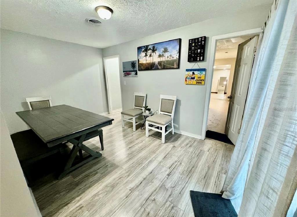 A dining room features a dark wood table, three chairs, and light wood-look flooring — 5832 HOLMES DRIVE, ORLANDO, FL