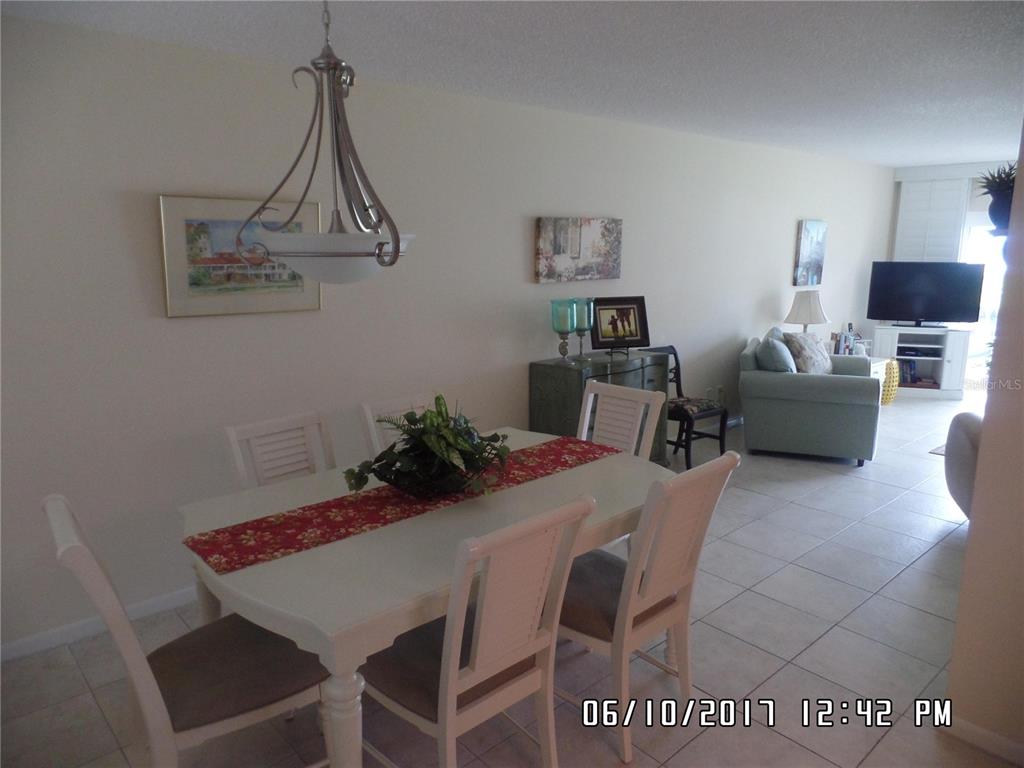 A dining area with a white table and chairs sits adjacent to a living room — 815 OCEAN SHORE BOULEVARD UNIT 9, ORMOND BEACH, FL