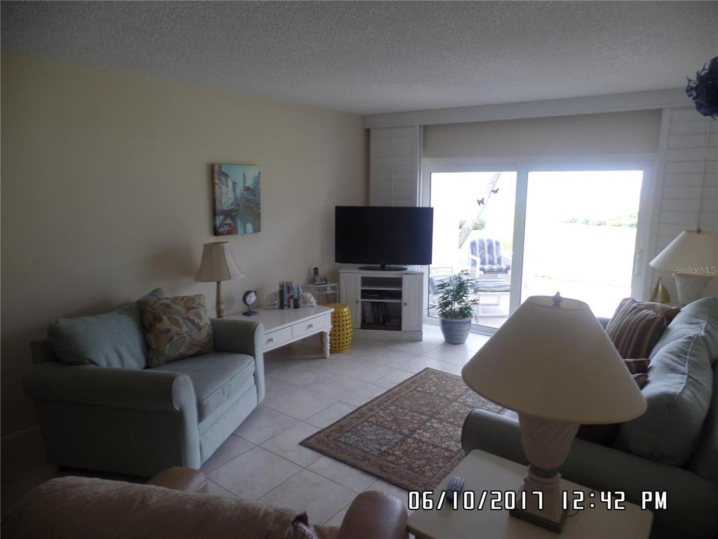 A living room features light tile floors, a television on a stand, and sliding glass doors — 815 OCEAN SHORE BOULEVARD UNIT 9, ORMOND BEACH, FL