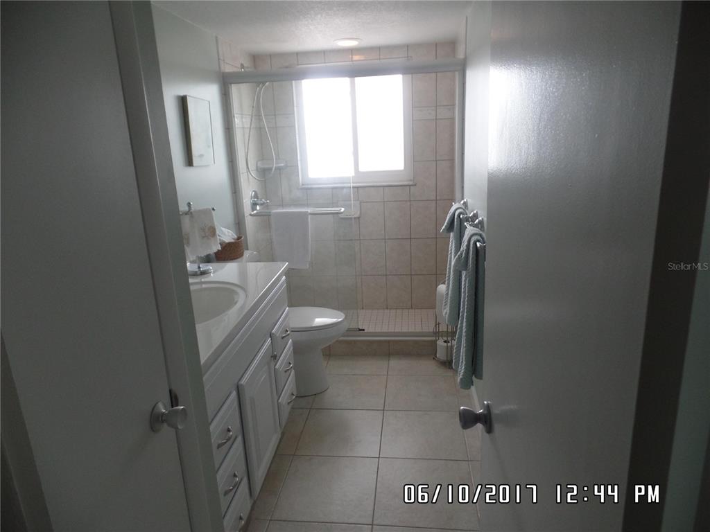 A bathroom features a white vanity, a toilet, and a glass-enclosed shower with tiled walls — 815 OCEAN SHORE BOULEVARD UNIT 9, ORMOND BEACH, FL