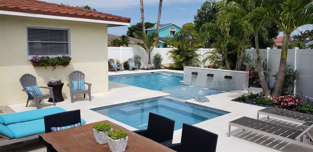 A backyard features a swimming pool, a spa, a water feature, and patio furniture — 430 173RD AVENUE E, NORTH REDINGTON BEACH, FL