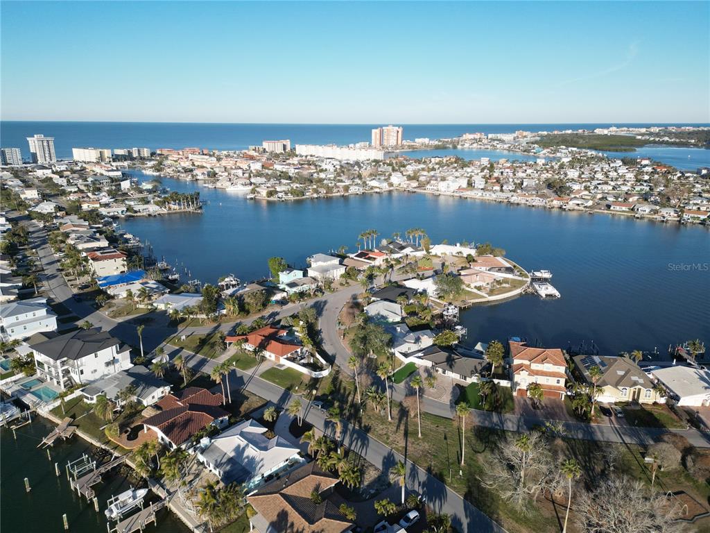 An aerial view shows a coastal neighborhood with houses, docks, and a bay — 430 173RD AVENUE E, NORTH REDINGTON BEACH, FL