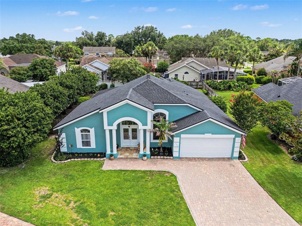 A single-story teal house with a two-car garage and a prominent arched entryway — 1986 CRYSTAL DOWNS COURT, OVIEDO, FL