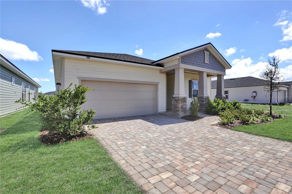 A single-story house with a two-car garage, stone-accented porch, and a paved driveway — 310 KNOTTED BIRCH AVENUE, ST AUGUSTINE, FL