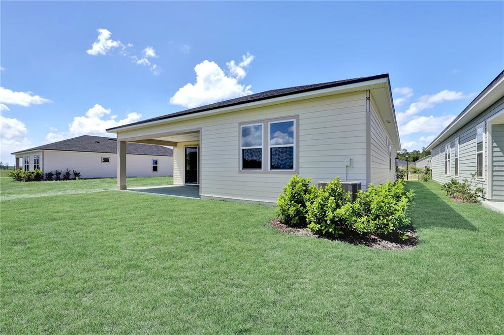 The exterior of a light-colored house features a covered patio and a grassy backyard — 310 KNOTTED BIRCH AVENUE, ST AUGUSTINE, FL