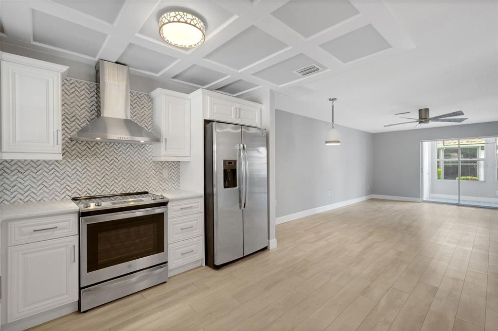 A kitchen features white cabinets, stainless steel appliances, a herringbone backsplash, and a coffered ceiling — 4602 PARK ACRES DRIVE UNIT 96, BRADENTON, FL