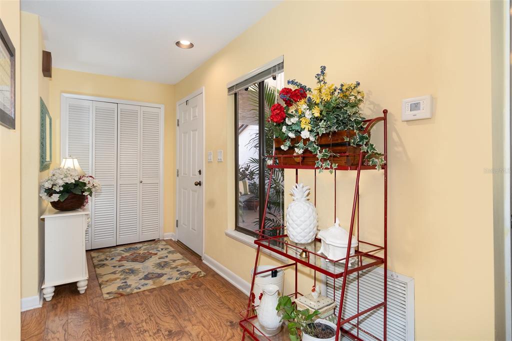 An entryway features wood-look flooring, yellow walls, a white closet, and a red metal shelf — 702 CLUSTERWOOD DRIVE, YALAHA, FL