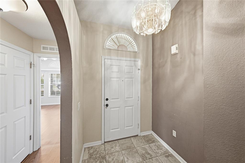 An entryway features a white front door with a fanlight, tile flooring, and a chandelier — 5638 ROYAL HILLS STREET, WINTER HAVEN, FL