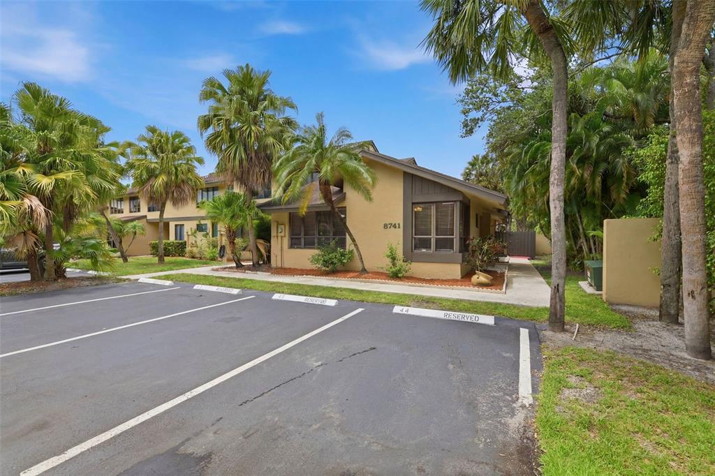 A tan multi-unit building with brown trim and palm trees sits behind reserved parking spaces — 8741 CLEARY BOULEVARD, FORT LAUDERDALE, FL