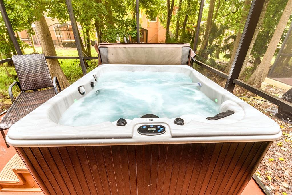 A hot tub sits on a screened-in patio surrounded by trees — 2725 COUPE STREET, KISSIMMEE, FL