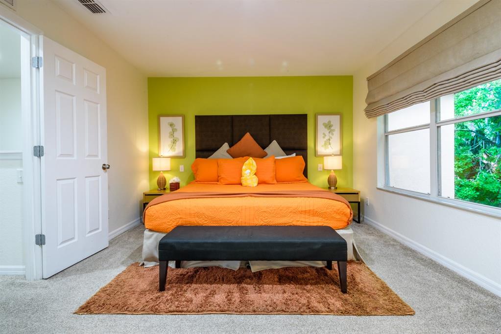 A bedroom features a lime green accent wall, orange bedding, and a black bench — 2725 COUPE STREET, KISSIMMEE, FL