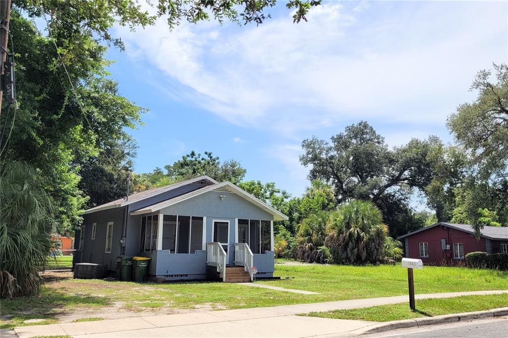 A gray, single-story house with a screened-in front porch sits on a grassy corner lot — 1542 29TH STREET, SARASOTA, FL