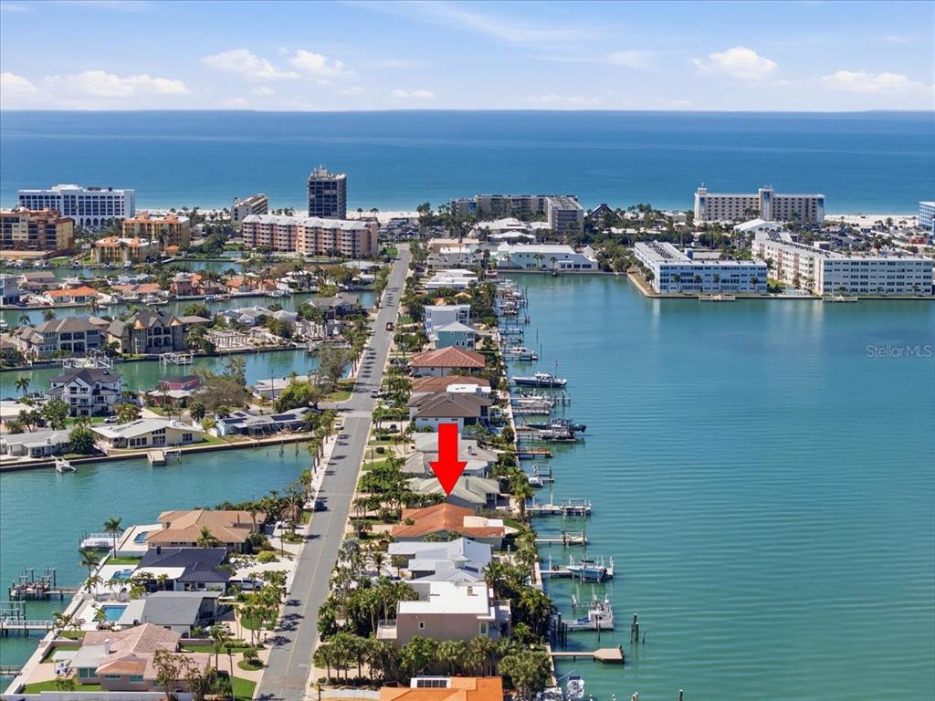 An aerial view shows waterfront homes along a street leading toward the ocean — 411 55TH AVENUE, ST PETE BEACH, FL