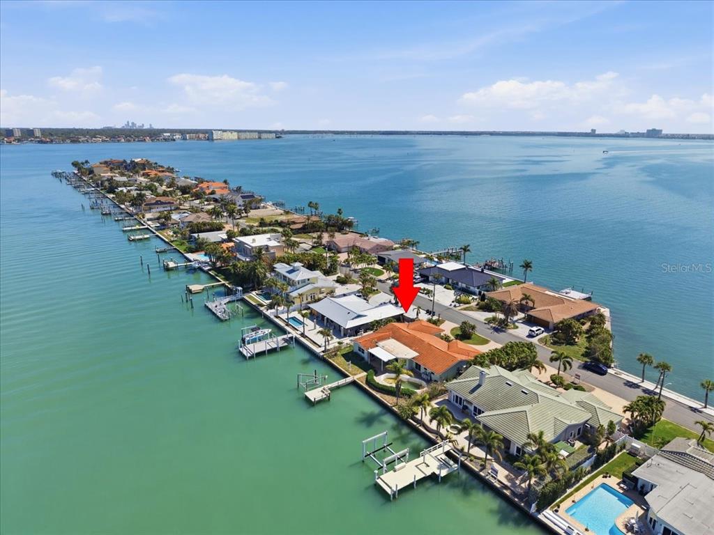 An aerial view shows a waterfront home with a red tile roof on a peninsula — 411 55TH AVENUE, ST PETE BEACH, FL