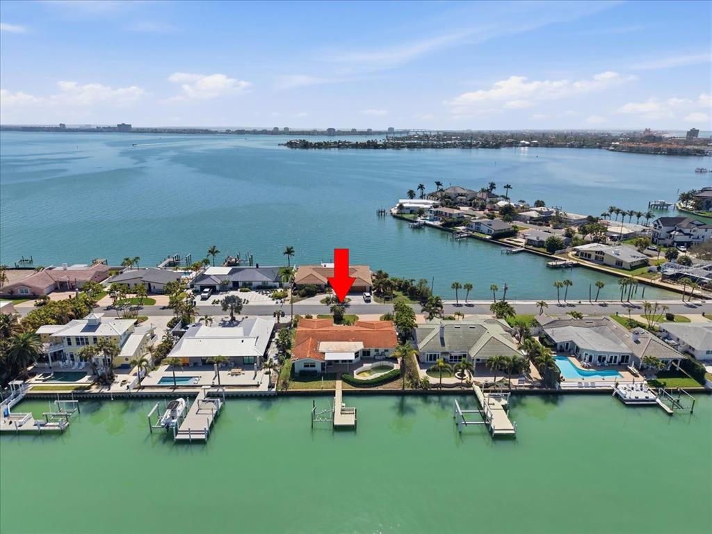 An aerial view of a waterfront house with a red arrow pointing to the roof — 411 55TH AVENUE, ST PETE BEACH, FL