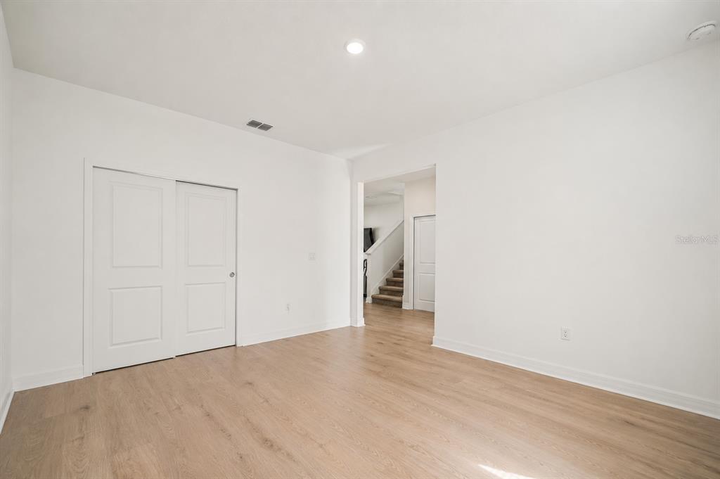 A room with white walls, light wood-look flooring, and a white sliding closet door — 1304 SILO DRIVE, ST CLOUD, FL