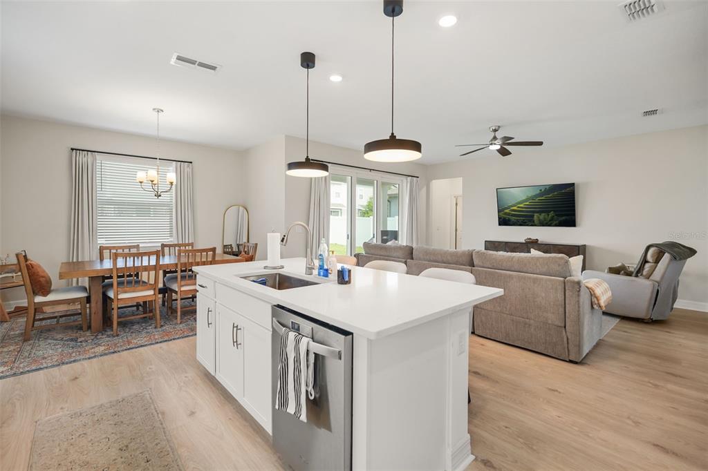 An open-concept kitchen with a white island and stainless steel appliances overlooks a living area — 1304 SILO DRIVE, ST CLOUD, FL