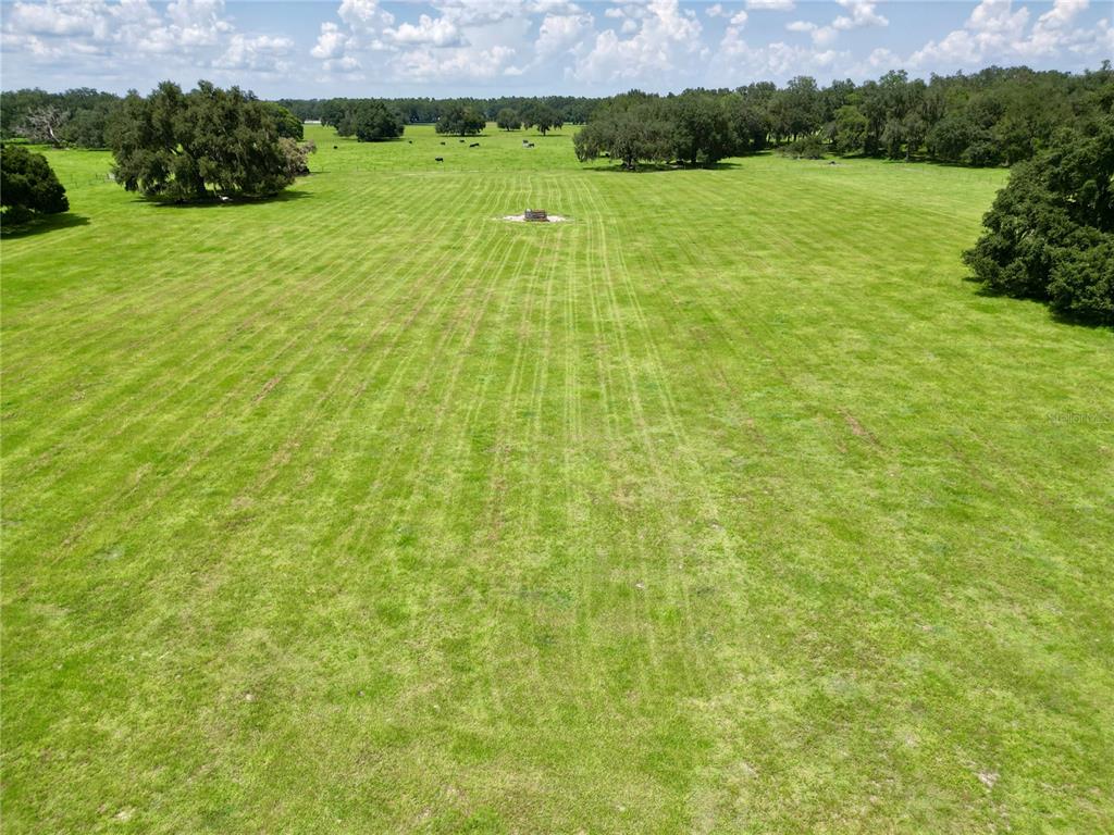 An aerial view of a large, flat, grassy pasture with scattered trees and a small structure — 0 W C-478, WEBSTER, FL
