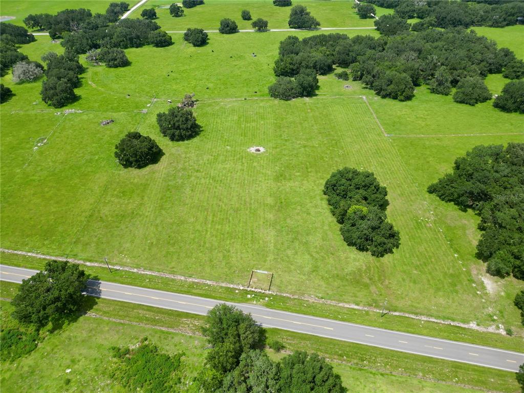 An aerial view shows a large, grassy pasture with scattered trees and a paved road — 0 W C-478, WEBSTER, FL