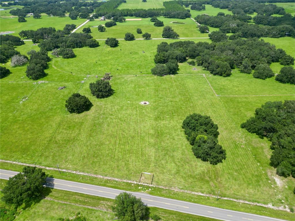 An aerial view of a large, grassy pasture with scattered trees and a paved road — 0 W C-478, WEBSTER, FL