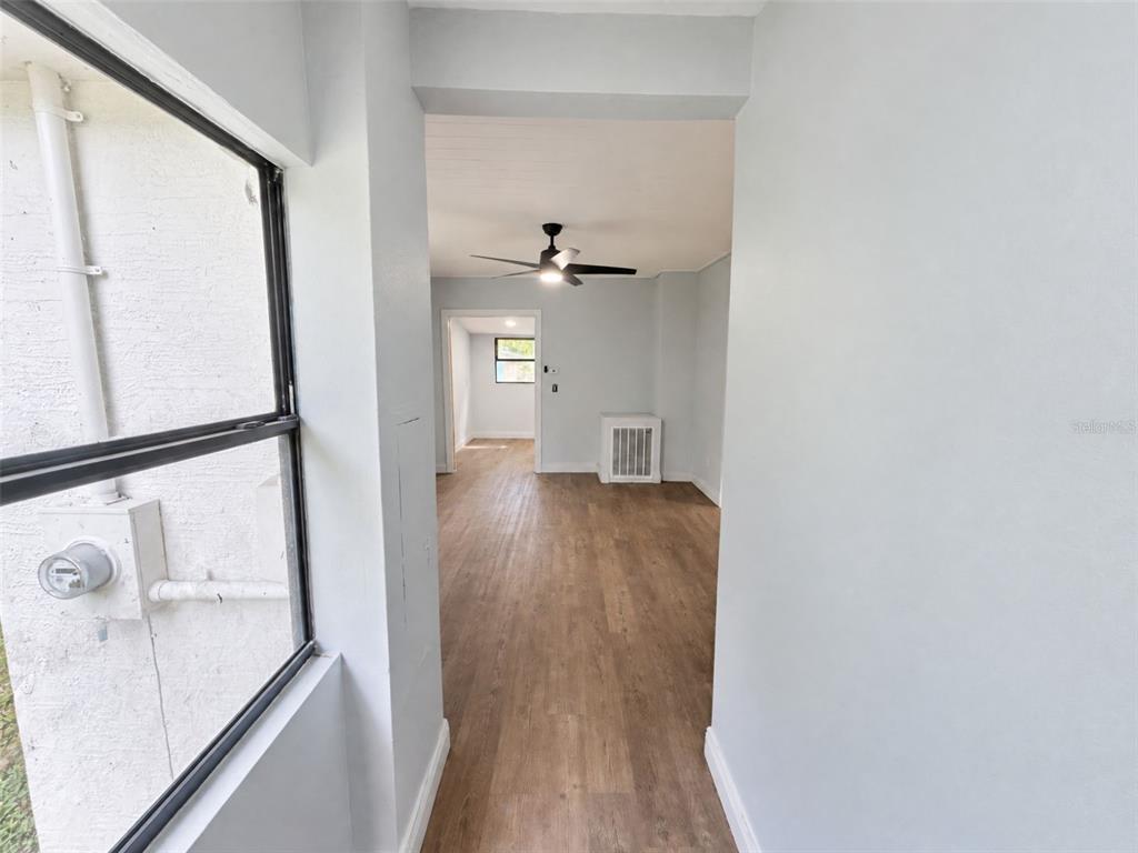 A view through a doorway into a living area with wood-look flooring and a ceiling fan — 16170 HURBAN STREET, BROOKSVILLE, FL