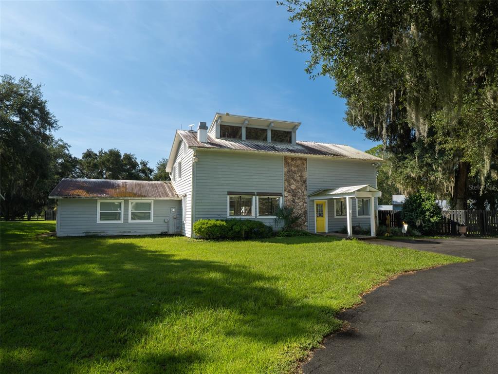 A two-story house with light blue siding, a stone chimney, and a metal roof — 9255 NW 115TH AVENUE, OCALA, FL