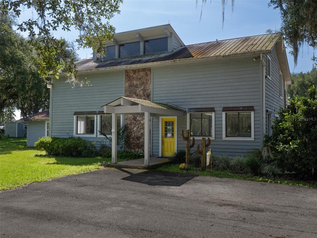 A two-story house with gray siding, a stone accent wall, and a bright yellow front door — 9255 NW 115TH AVENUE, OCALA, FL