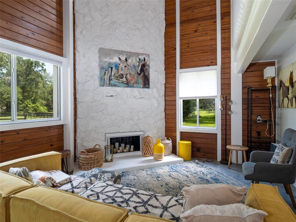 A living room features a white stone fireplace, wood-paneled walls, and a yellow sectional sofa — 9255 NW 115TH AVENUE, OCALA, FL