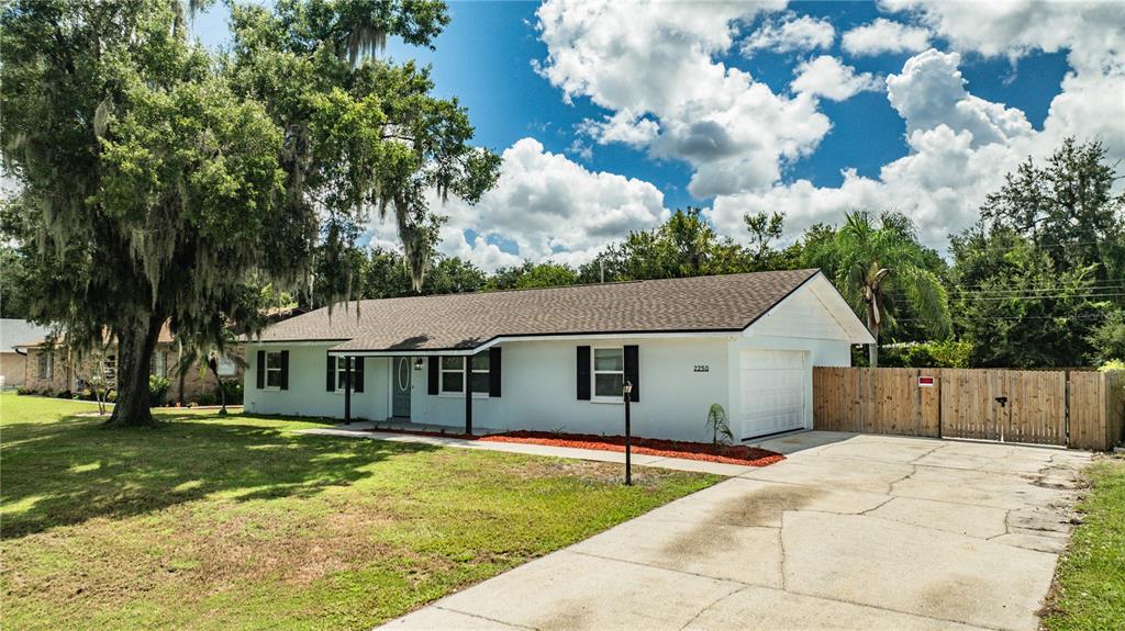 A white single-story house with a brown roof, black shutters, and a concrete driveway — 2250 MAPLE HILL DRIVE, LAKELAND, FL