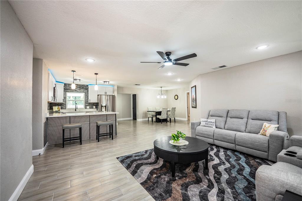 An open-concept living area features a kitchen with a breakfast bar, dining space, and sofa — 2250 MAPLE HILL DRIVE, LAKELAND, FL