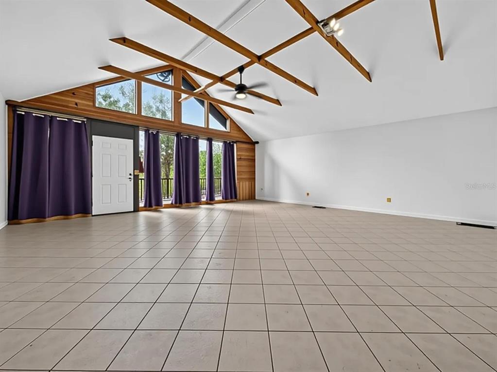 A large, open room features vaulted ceilings with exposed wood beams, tile flooring, and windows — 14820 COUNTY ROAD 48, ASTATULA, FL