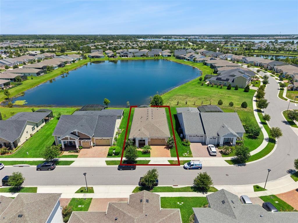 An aerial view shows a single-family house with a red outline bordering a lake — 2665 MEADOWEDGE LOOP, ST CLOUD, FL