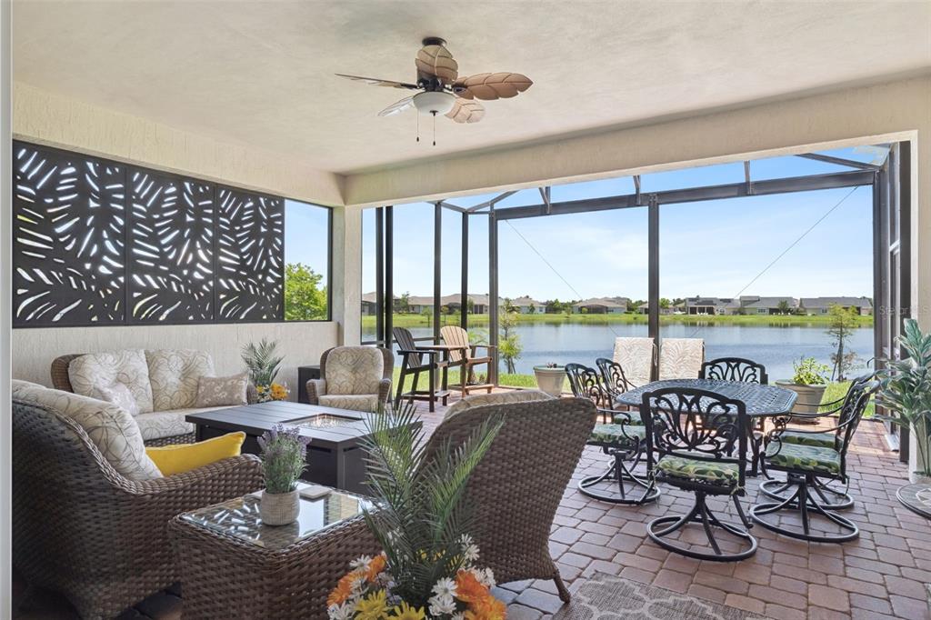 A covered patio with wicker furniture, a fire pit, and a screened view of a lake — 2665 MEADOWEDGE LOOP, ST CLOUD, FL