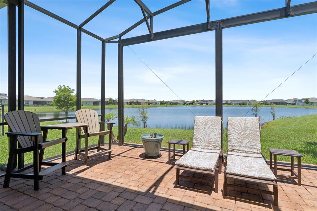 A screened-in patio features brick pavers, outdoor furniture, and a view of a lake — 2665 MEADOWEDGE LOOP, ST CLOUD, FL