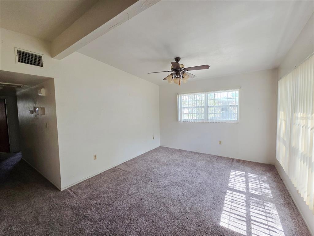 An empty room with beige carpet, white walls, a ceiling fan, and vertical window blinds — 640 FORREST DR, BARTOW, FL