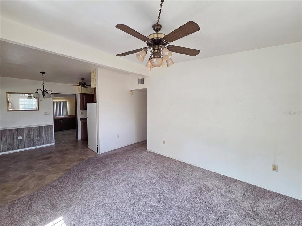A carpeted living room features a ceiling fan and an adjacent kitchen with wood paneling — 640 FORREST DR, BARTOW, FL