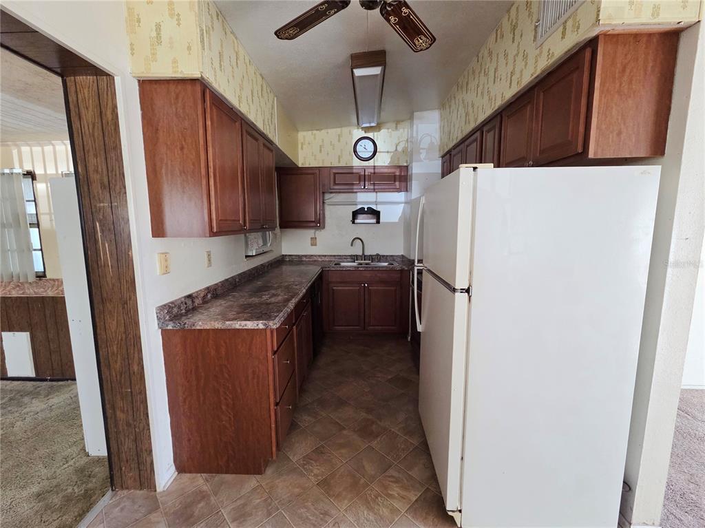 A galley kitchen features dark wood cabinets, laminate countertops, and a white refrigerator — 640 FORREST DR, BARTOW, FL