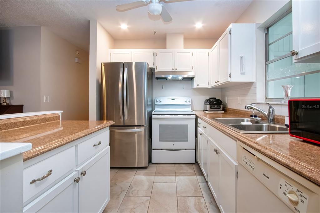 A kitchen features white cabinets, stainless steel appliances, a white stove, and granite countertops — 2228 GREENHAVEN DRIVE UNIT 384, SUN CITY CENTER, FL