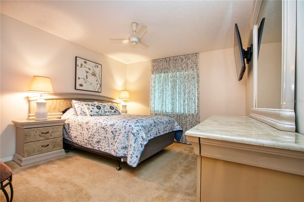 A bedroom features a bed with a floral quilt, two nightstands, and a dresser — 2228 GREENHAVEN DRIVE UNIT 384, SUN CITY CENTER, FL