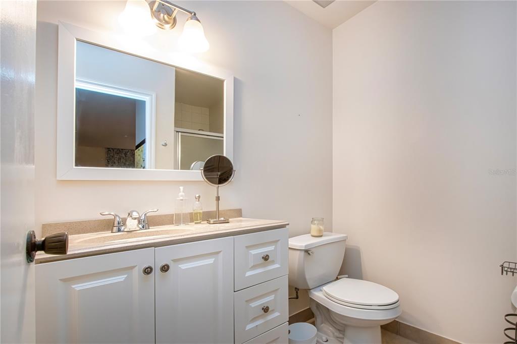 A bathroom features a white vanity with a stone countertop, a mirror, and a toilet — 2228 GREENHAVEN DRIVE UNIT 384, SUN CITY CENTER, FL