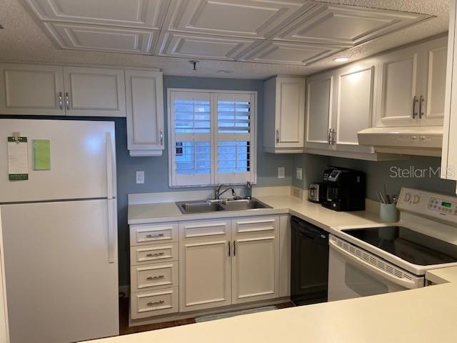 A kitchen features white cabinets, a white refrigerator, a black dishwasher, and a tiled ceiling — 1001 BENJAMIN FRANKLIN DRIVE UNIT 507, SARASOTA, FL