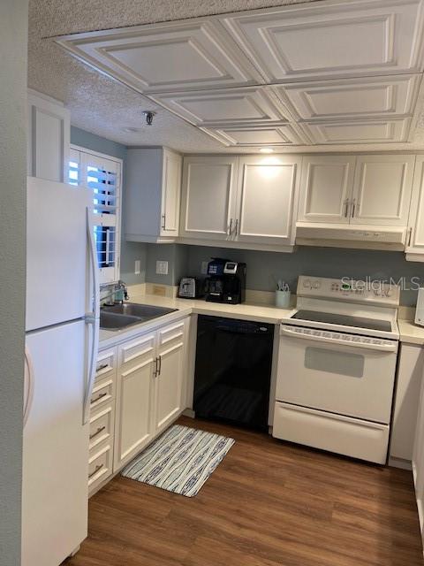 A kitchen features white cabinets, a black dishwasher, a white stove, and wood-look flooring — 1001 BENJAMIN FRANKLIN DRIVE UNIT 507, SARASOTA, FL