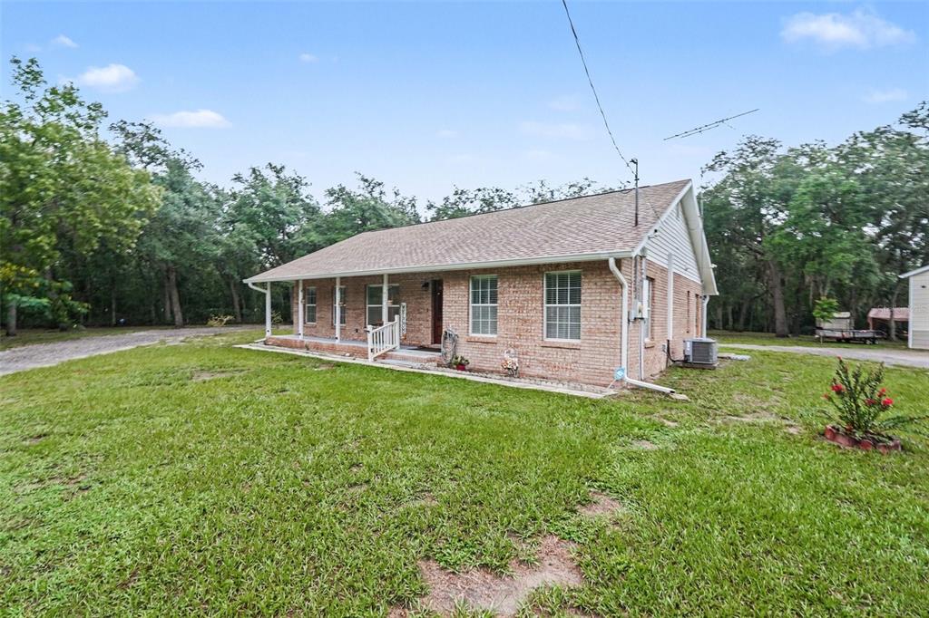 A single-story brick house with a covered front porch sits on a grassy lot — 9172 KEDRONE DRIVE, WEBSTER, FL