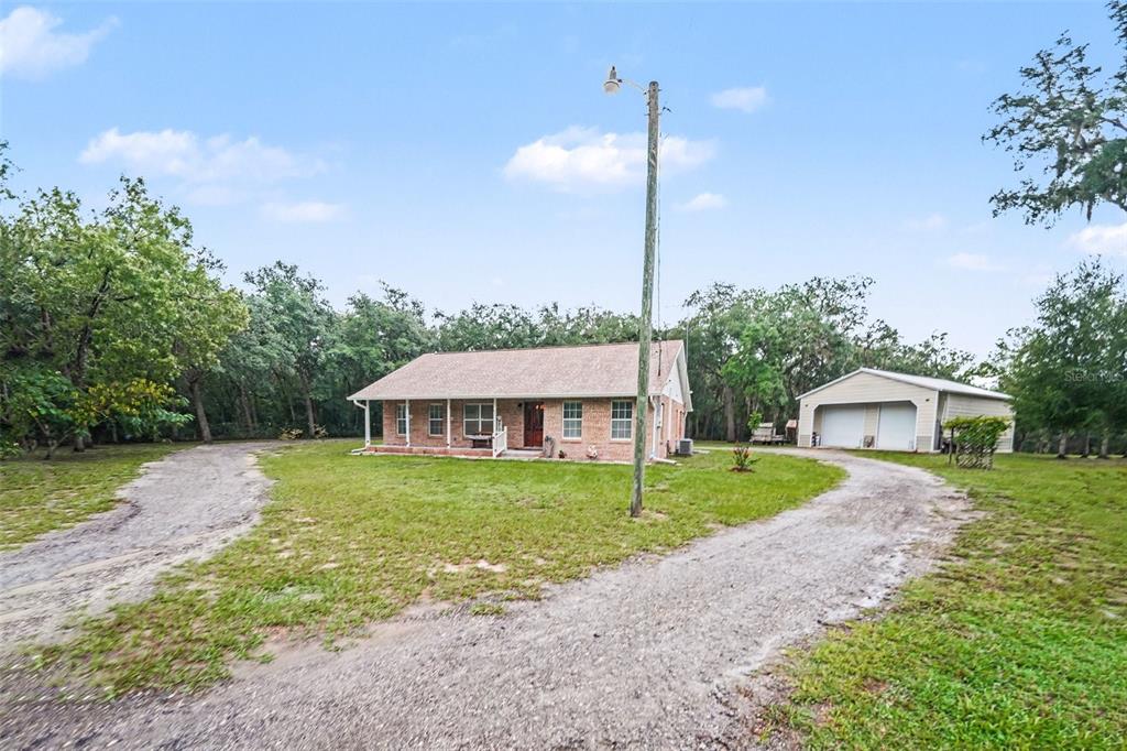 A brick house with a covered porch and a detached garage sits on a grassy lot — 9172 KEDRONE DRIVE, WEBSTER, FL